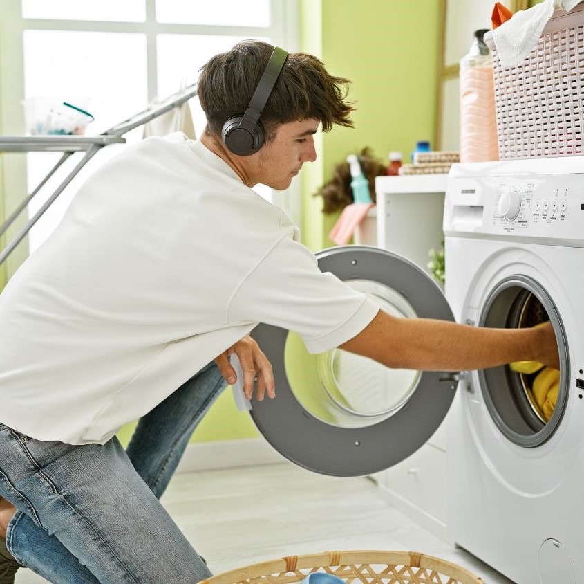 Young person doing laundry with headphones